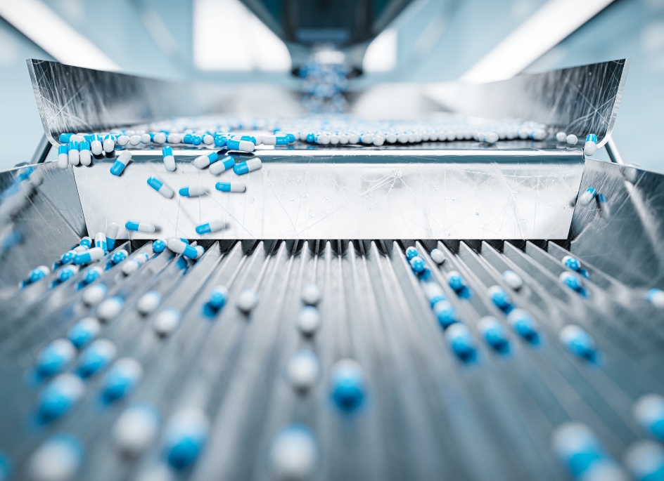 Hundreds of blue and white capsules moving down a manufacturing line.