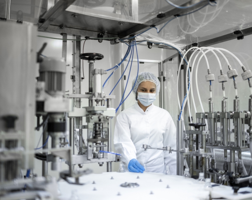 Woman covered with PPE examining a clean and orderly nutraceutical manufacturing system.