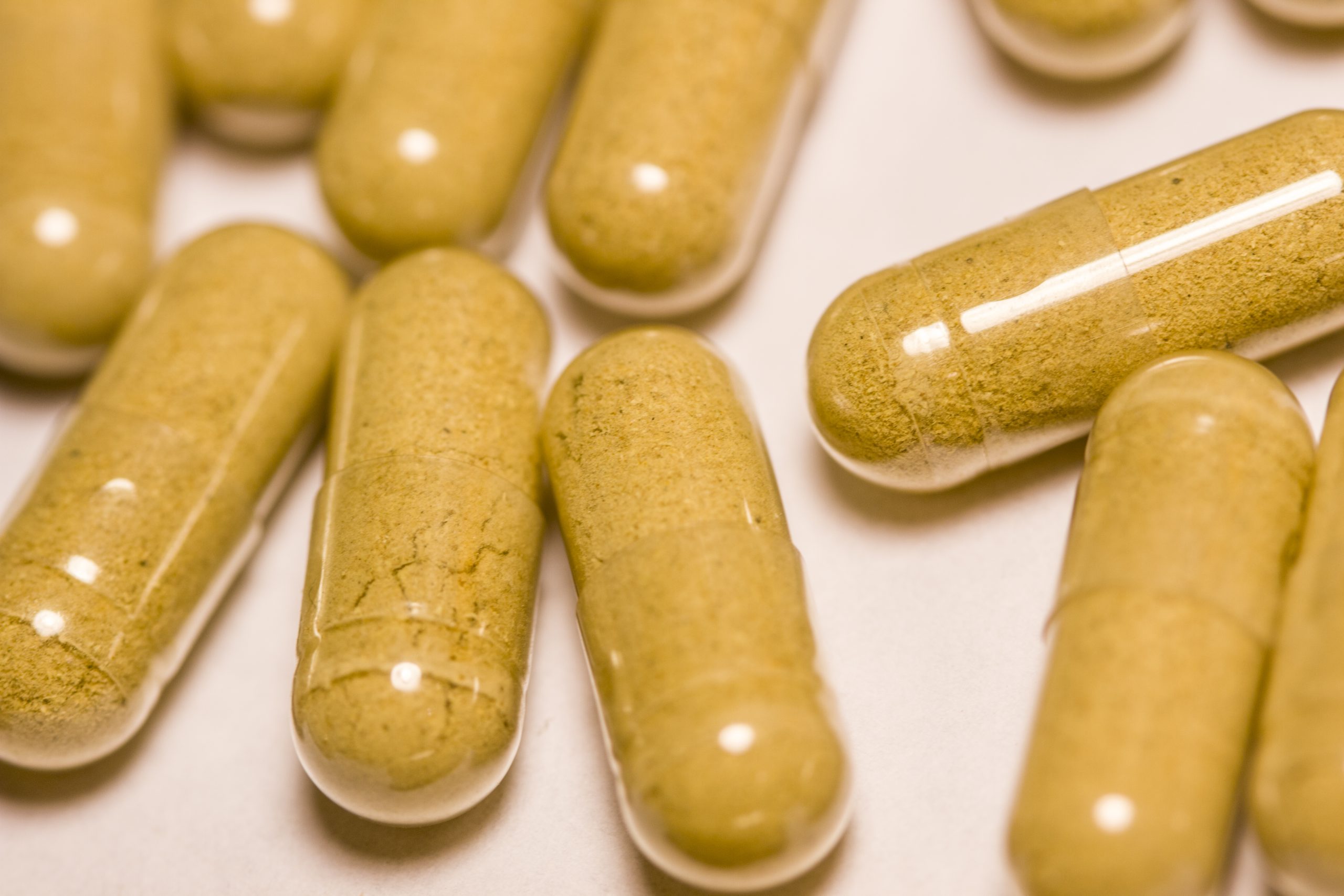 Closeup of a collection of bright orange capsules filled with turmeric.