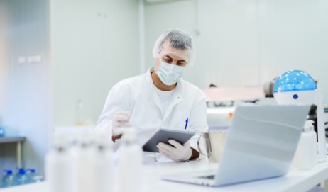 Man covered with PPE doing a quality assurance check on nutraceutical products.