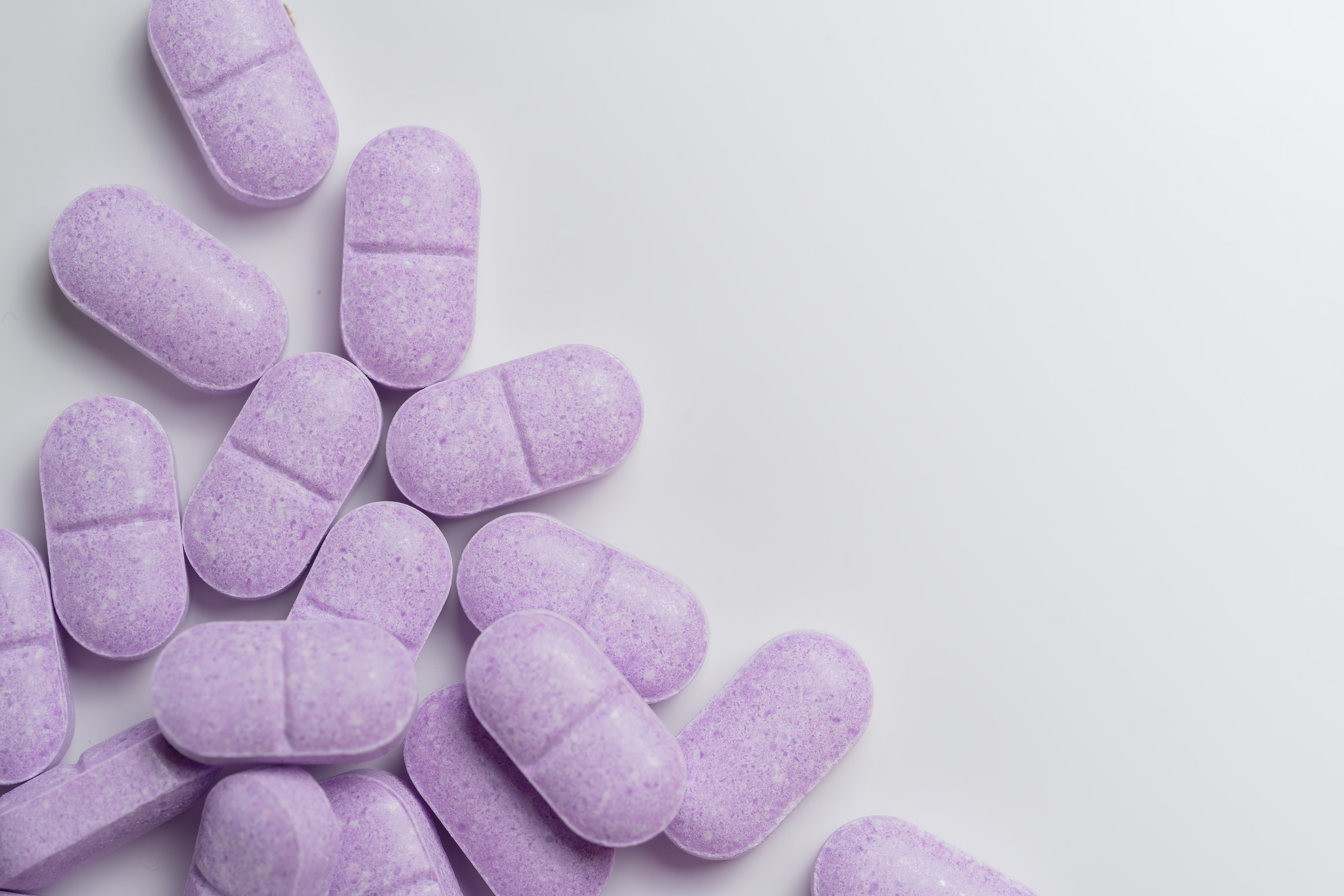 Purple scored chewable Vitamin C tablets arranged in a random cluster.