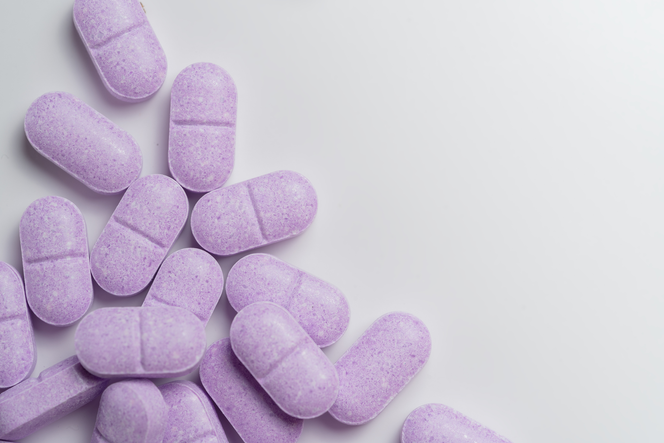 Purple scored chewable Vitamin C tablets arranged in a random cluster.