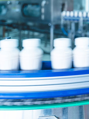White nutraceutical bottles moving down a high-speed conveyor belt.