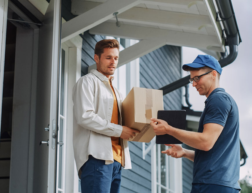 Delivery man asking another man to sign for a package that's being delivered to his home.